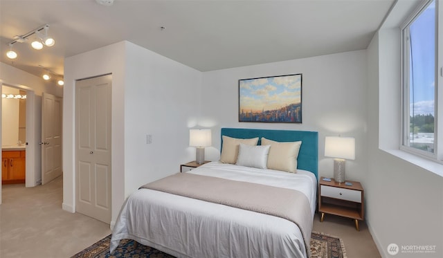 300 110th Ave NE Unit 605, Bellevue, WA 98004 - bedroom with light carpet, a closet, ensuite bathroom, track lighting, and baseboards