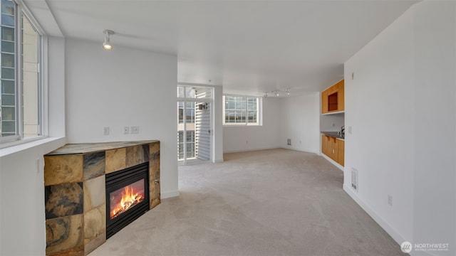 300 110th Ave NE Unit 605, Bellevue, WA 98004 - unfurnished living room featuring rail lighting, a tile fireplace, light carpet, and baseboards