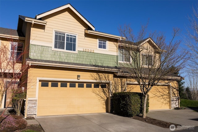 craftsman-style house with an attached garage, stone siding, and driveway