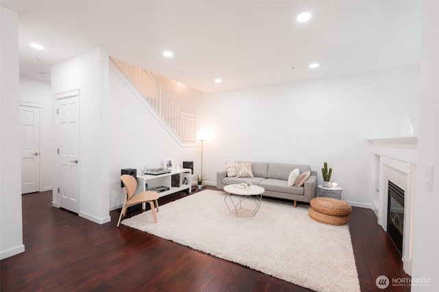 living area featuring recessed lighting, baseboards, stairway, dark wood-style flooring, and a high end fireplace