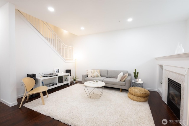 living room featuring baseboards, a high end fireplace, dark wood-style flooring, and recessed lighting