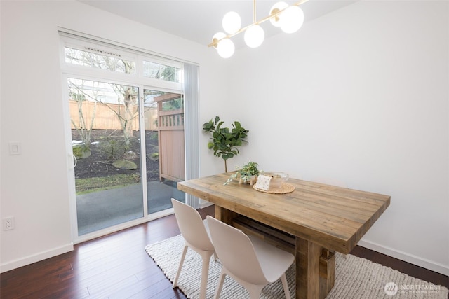 dining area featuring a chandelier, dark wood-style flooring, and baseboards