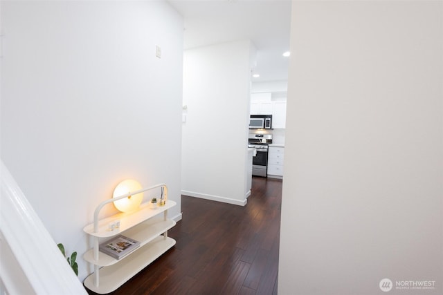 hall featuring dark wood-style flooring and baseboards