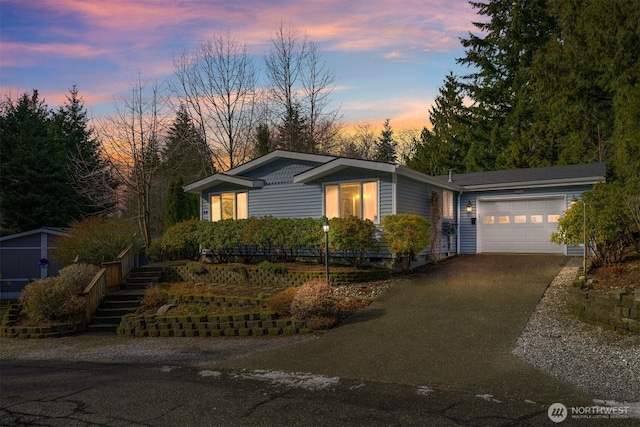 ranch-style house with a garage, stairway, and aphalt driveway