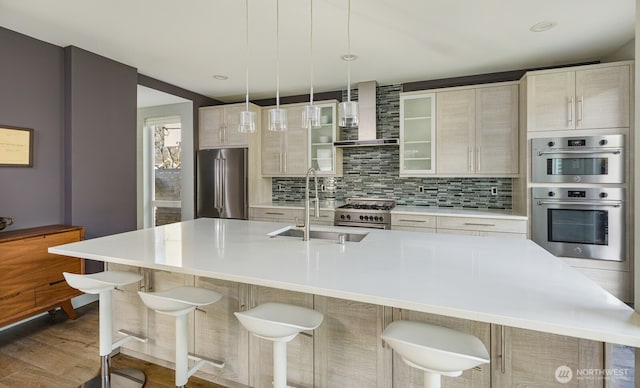 kitchen with high quality appliances, light countertops, a sink, and a center island with sink