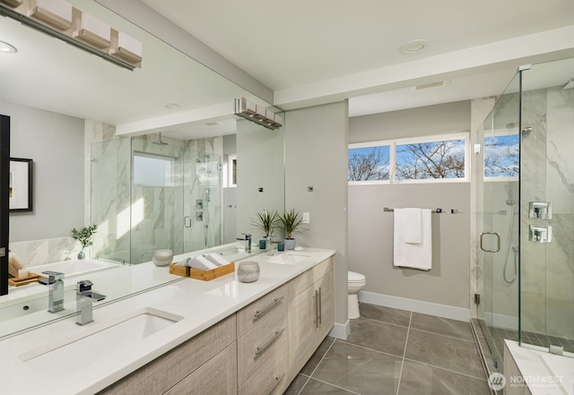 bathroom featuring double vanity, a marble finish shower, baseboards, and a sink