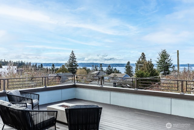 wooden deck with an outdoor fire pit and a water view