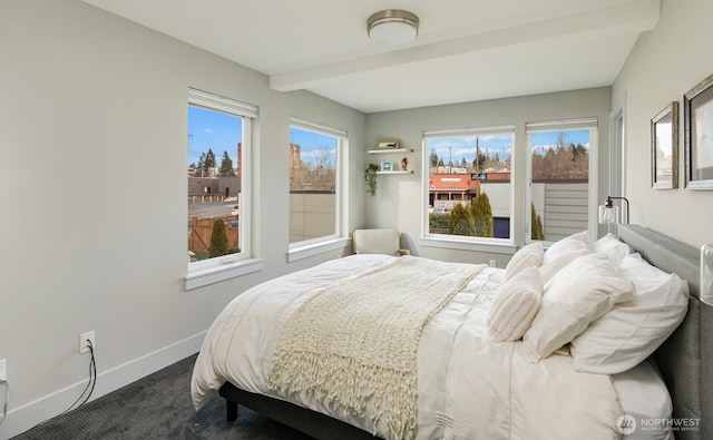 bedroom with beamed ceiling, dark carpet, and baseboards