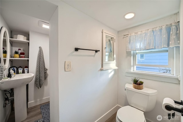 bathroom featuring toilet, a sink, baseboards, and wood finished floors