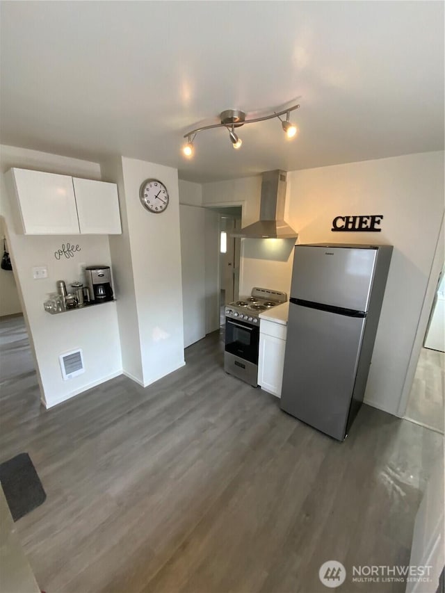 kitchen with light countertops, stove, freestanding refrigerator, white cabinetry, and extractor fan