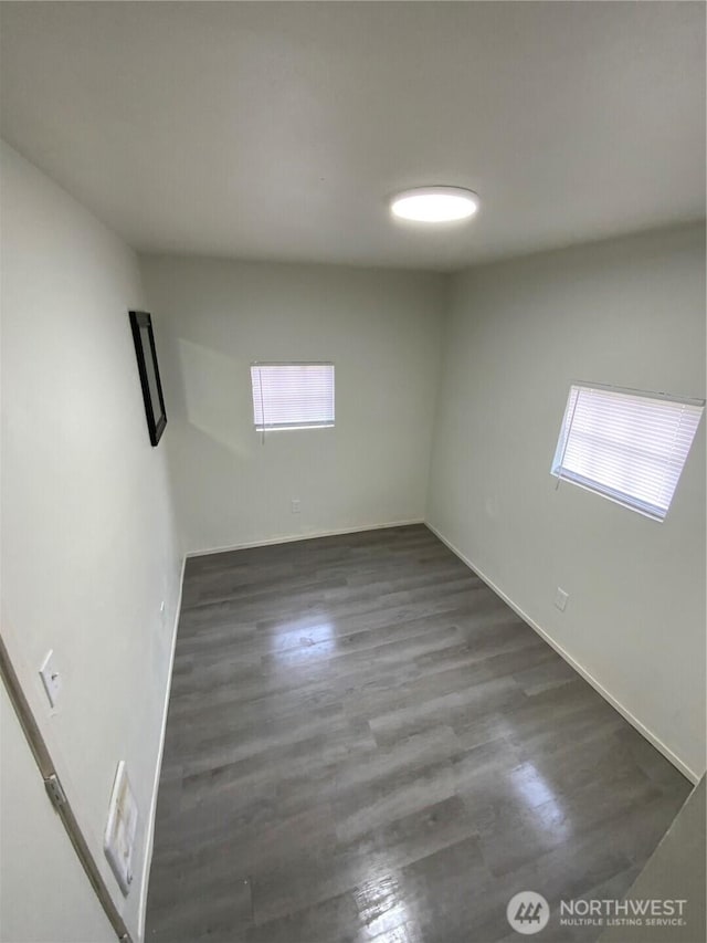 spare room featuring dark wood finished floors and a healthy amount of sunlight