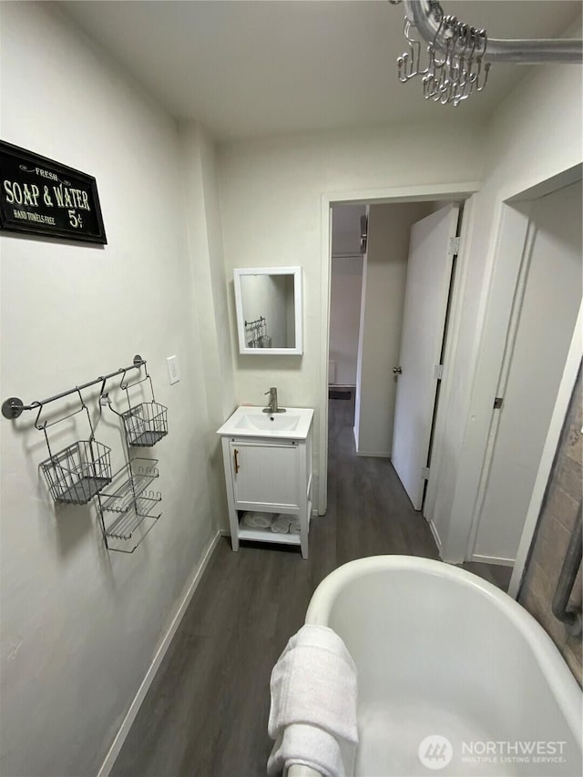 full bathroom with wood finished floors, a freestanding tub, vanity, and baseboards