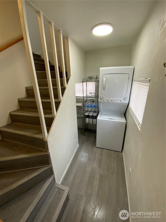 laundry room featuring laundry area, stacked washing maching and dryer, and wood finished floors