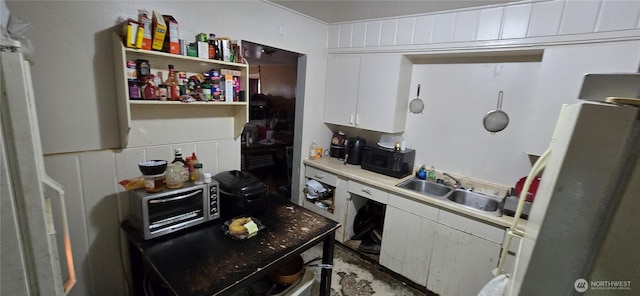 kitchen featuring white cabinets, freestanding refrigerator, light countertops, open shelves, and a sink