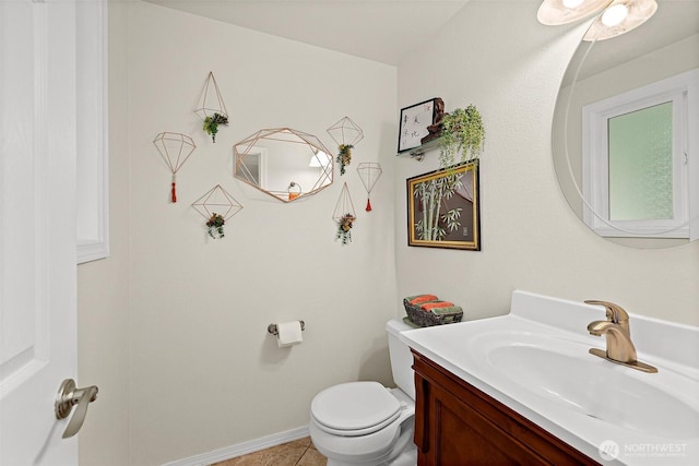 half bathroom with tile patterned flooring, baseboards, vanity, and toilet