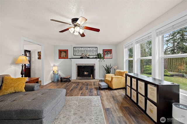 living room with dark wood-style floors, ceiling fan, a textured ceiling, and baseboards