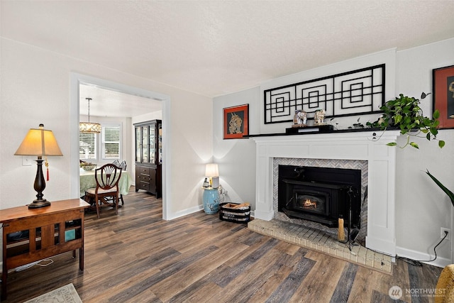 living area featuring a textured ceiling, dark wood-type flooring, and baseboards