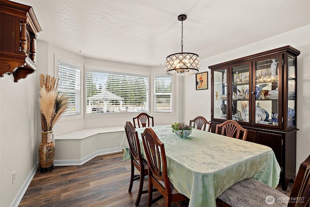 dining space featuring dark wood-style floors, a textured ceiling, and baseboards