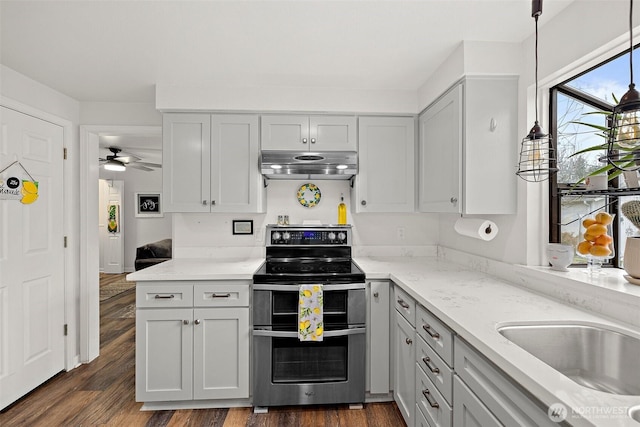 kitchen with under cabinet range hood, double oven range, dark wood finished floors, and decorative light fixtures