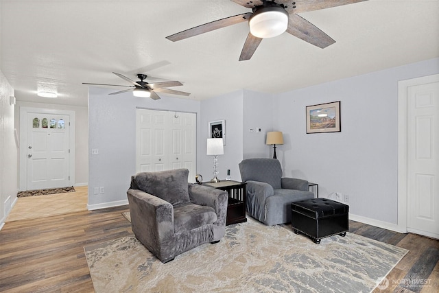 living area featuring ceiling fan, baseboards, and wood finished floors