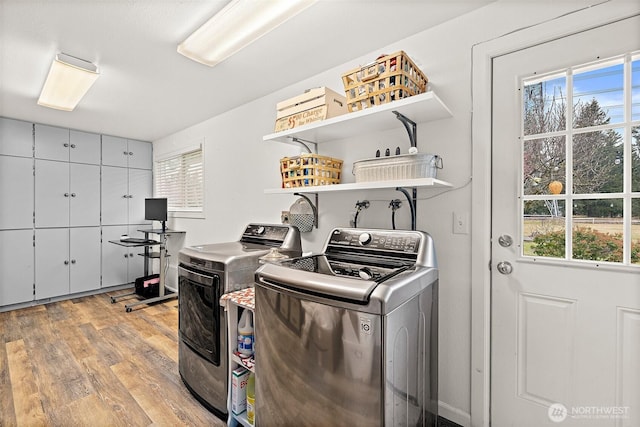 washroom featuring laundry area, a healthy amount of sunlight, light wood-style flooring, and washing machine and clothes dryer