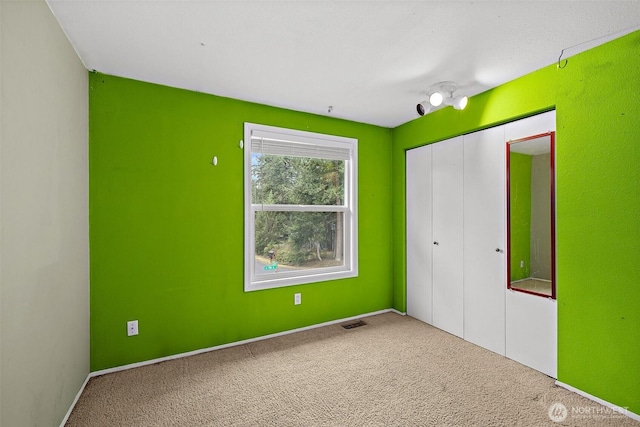 unfurnished bedroom with a closet, visible vents, and carpet flooring