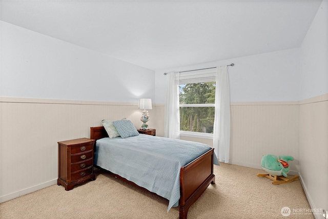 bedroom featuring wainscoting and light carpet