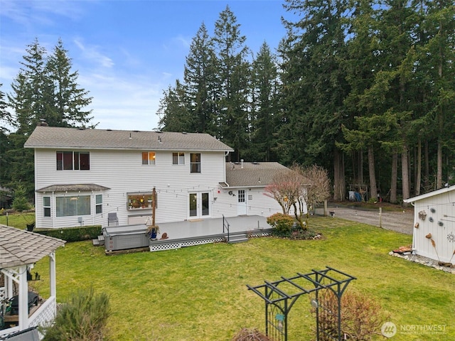 rear view of property with a hot tub, a deck, and a yard