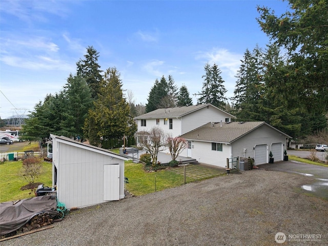 view of side of property featuring driveway, an attached garage, cooling unit, and a yard