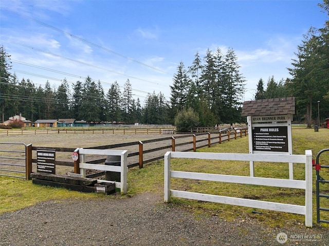 view of gate with fence, an enclosed area, and a rural view