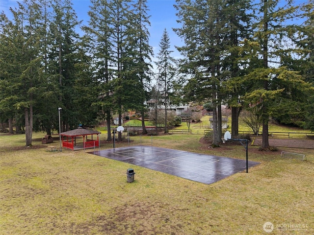 view of basketball court featuring fence, basketball court, and a lawn