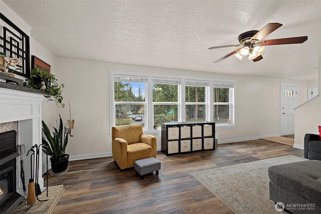 living room featuring dark wood-style floors, a glass covered fireplace, and a textured ceiling