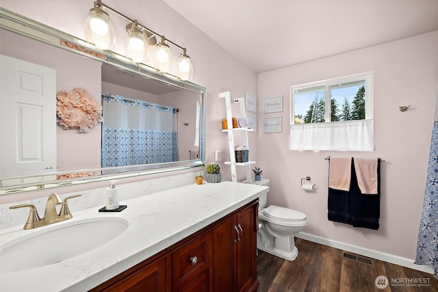 bathroom with toilet, wood finished floors, visible vents, vanity, and baseboards