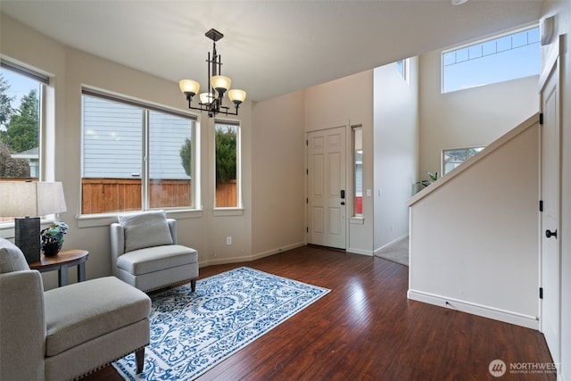 interior space featuring dark wood-style floors, an inviting chandelier, stairs, and baseboards