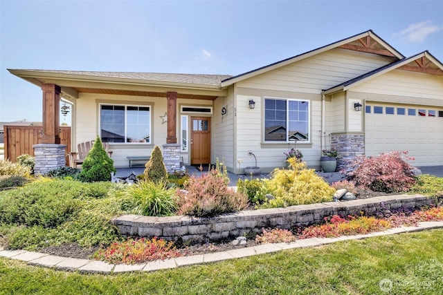 view of front of house with stone siding, covered porch, and an attached garage