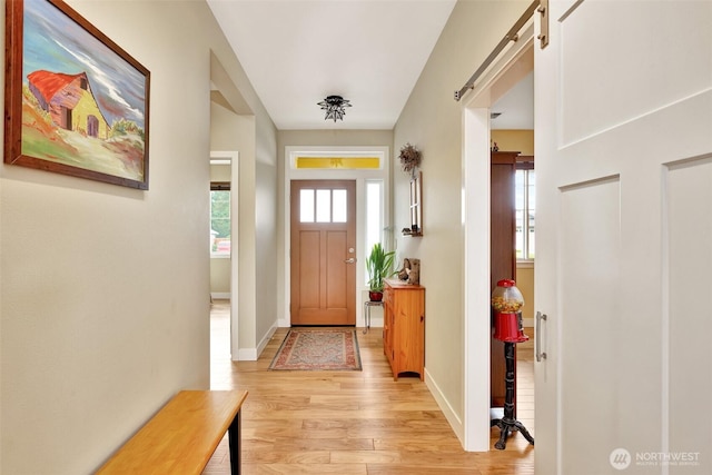 entryway featuring light wood-type flooring, a barn door, and baseboards