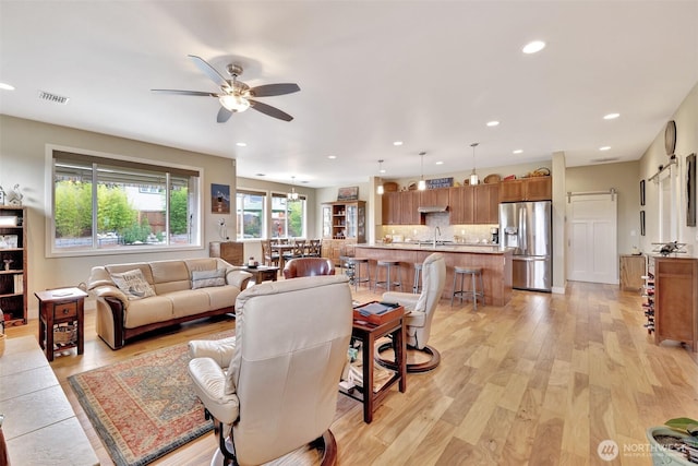 living area with ceiling fan, light wood finished floors, visible vents, and recessed lighting