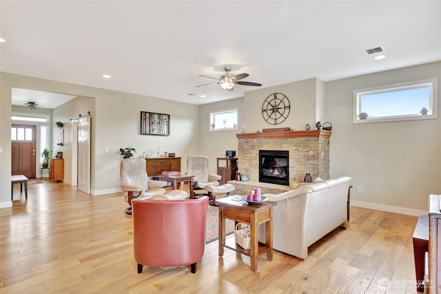 living room with a barn door, light wood-type flooring, visible vents, and baseboards