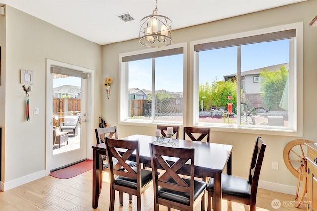 dining room featuring light wood-type flooring, an inviting chandelier, baseboards, and visible vents