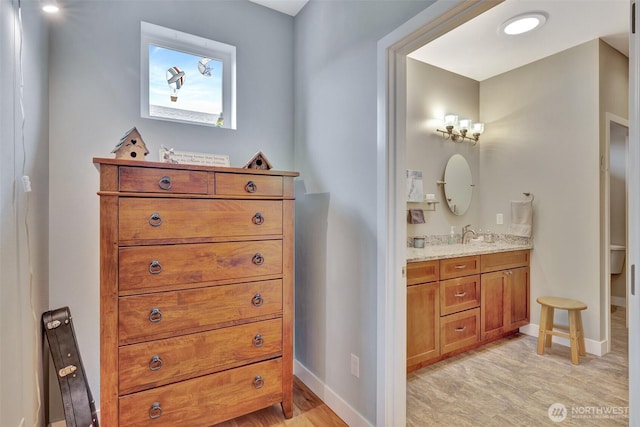 bathroom with toilet, vanity, baseboards, and wood finished floors