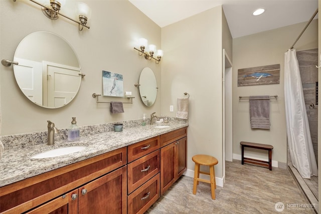 full bathroom with double vanity, curtained shower, a sink, and baseboards