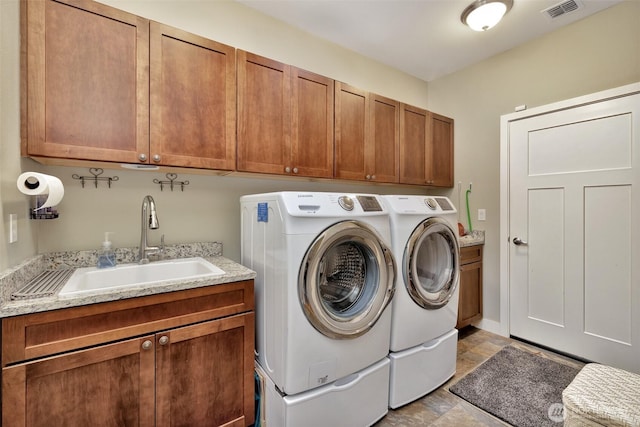 washroom with a sink, visible vents, independent washer and dryer, cabinet space, and stone finish flooring