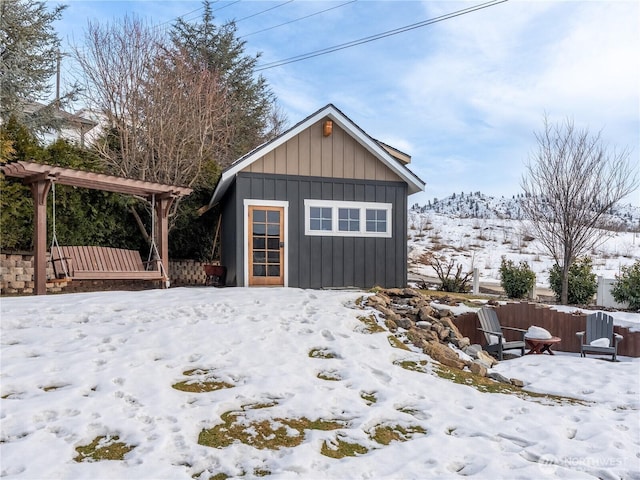 snow covered structure with an outbuilding and fence