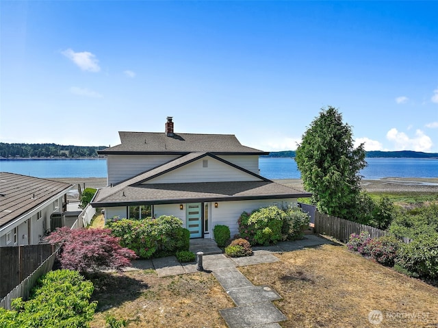 view of front of property with a water view, fence, and a chimney