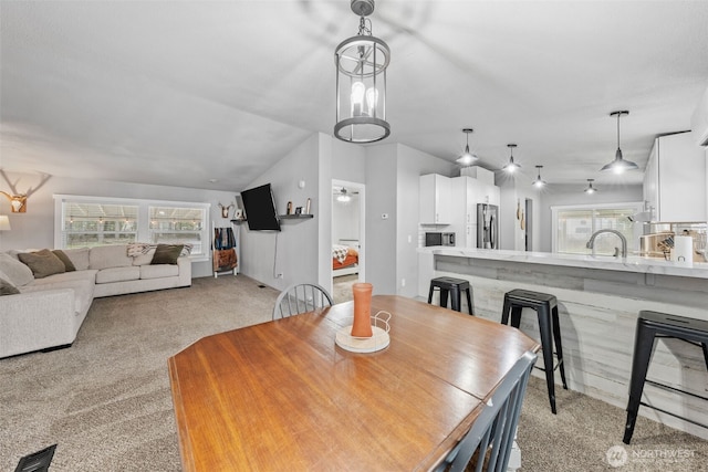 dining space featuring light carpet and vaulted ceiling