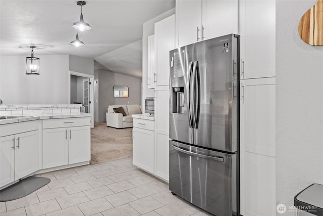 kitchen featuring white cabinetry, open floor plan, light countertops, hanging light fixtures, and stainless steel refrigerator with ice dispenser