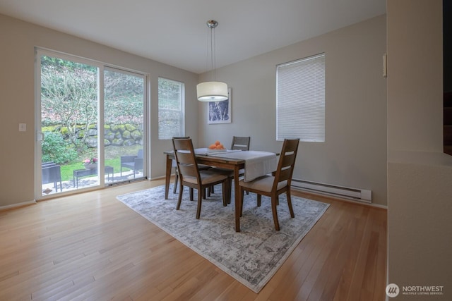 dining space featuring light wood-type flooring, baseboards, and a baseboard heating unit