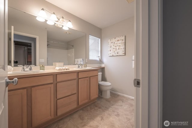 bathroom with double vanity, baseboards, toilet, and a sink