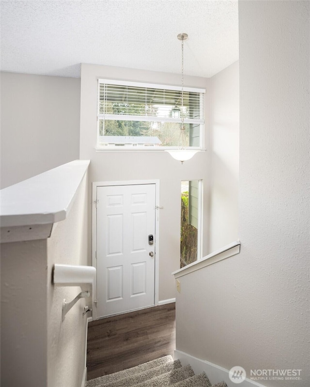 entryway with baseboards, stairway, a textured ceiling, and wood finished floors