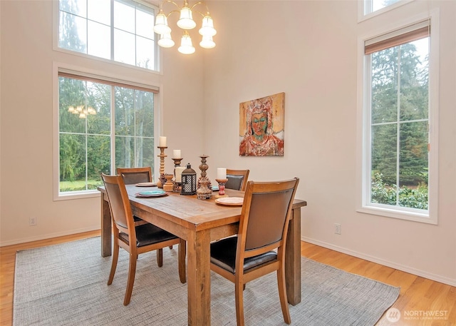 dining space featuring baseboards, light wood-type flooring, and an inviting chandelier